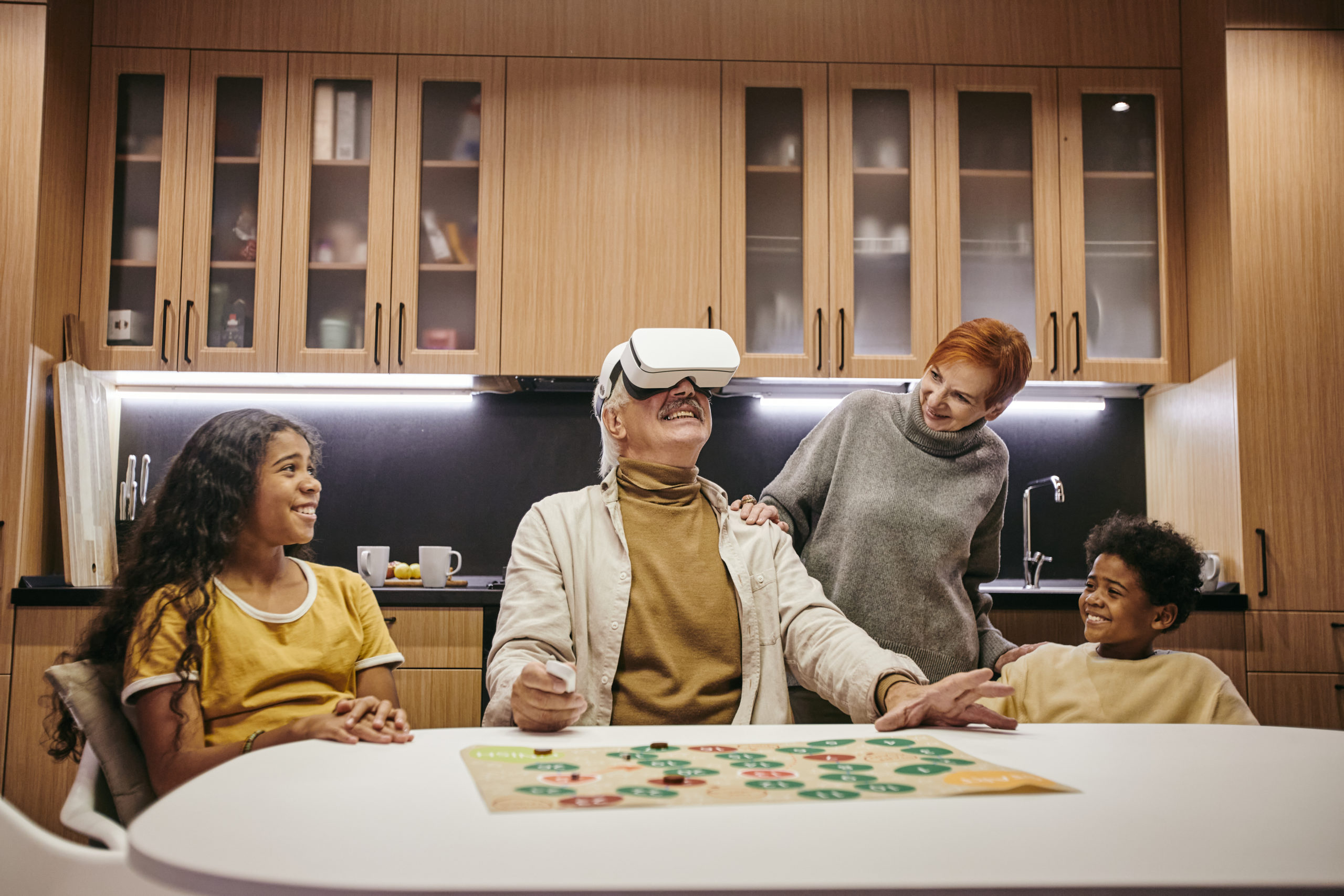 Two cute siblings and their grandmother looking at mature man in vr headset